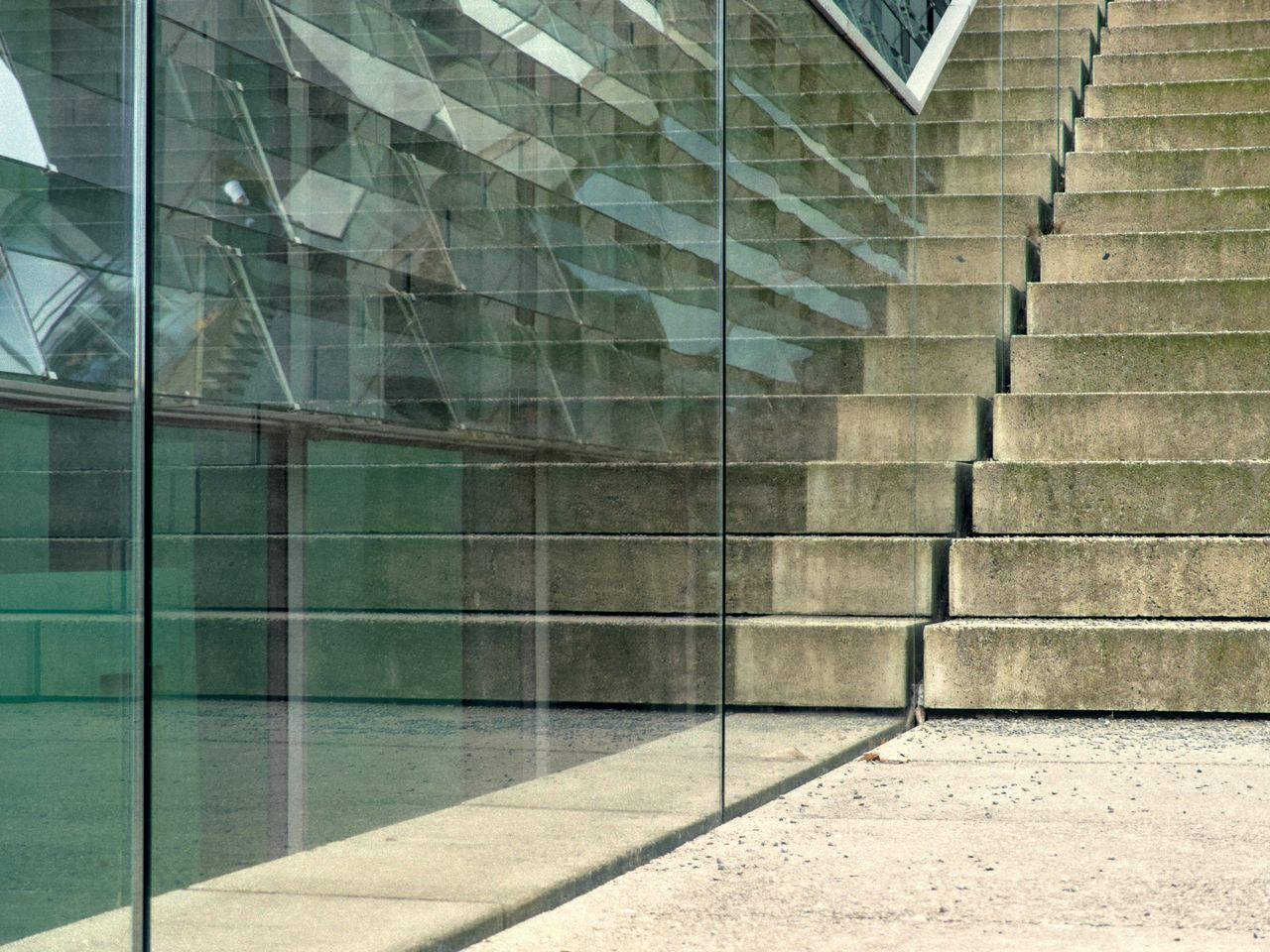 A modern staircase with glass reflections creating an abstract architectural perspective.